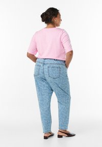 Rozā un baltā svītrainā īsās piedurknes augšdaļa, kas apvienota ar gaiši ziliem džinsiem ar lapu rakstu un aizmugurējām kabatām.