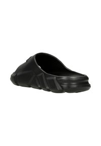 Black slip-on shoe featuring a textured rubber sole, streamlined design, and a rigid outer structure with angular accents.