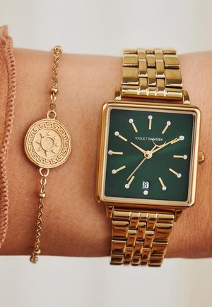Montre carrée en or avec un cadran vert, index horaires en cristal et bracelet en maillon de chaîne, accompagnée d'un bracelet en or orné d'un motif solaire circulaire.