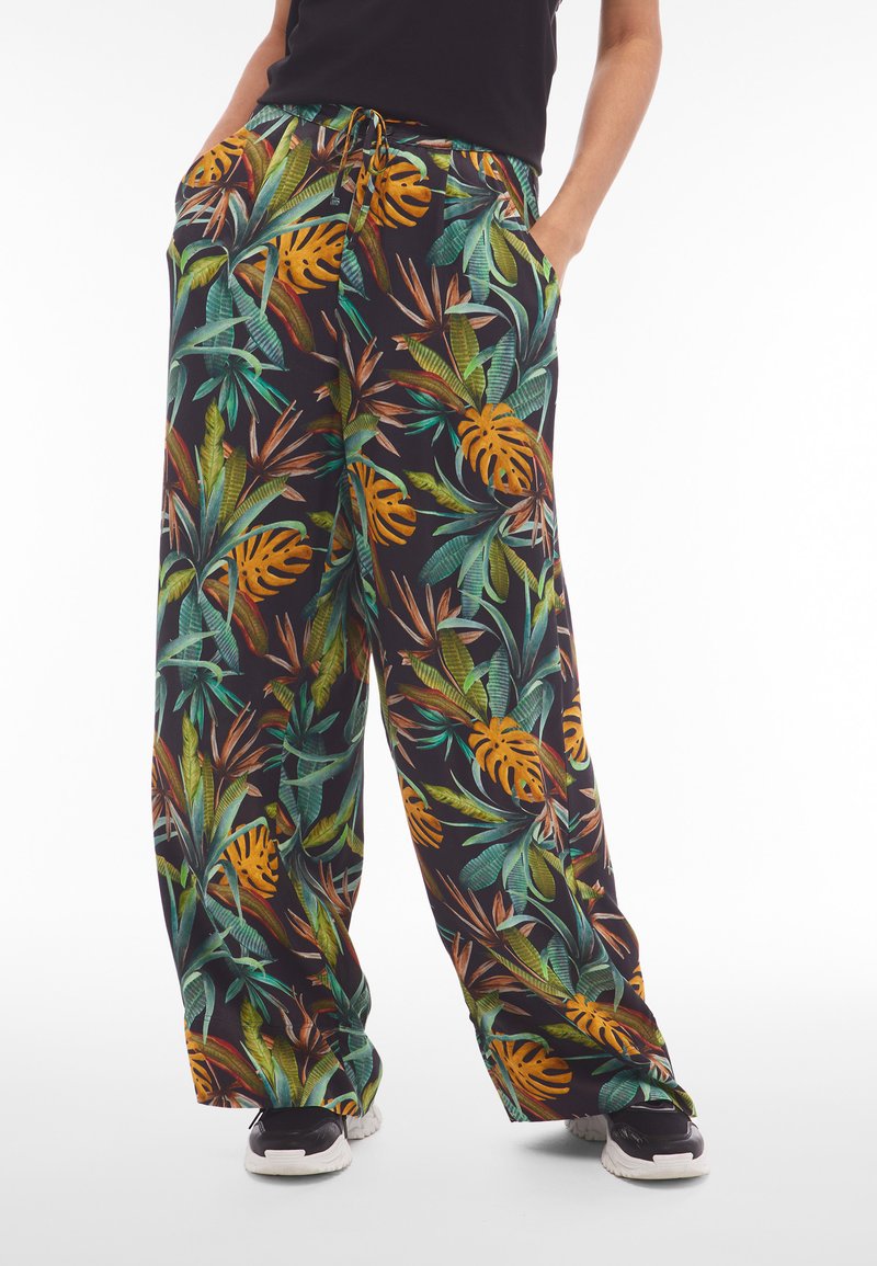 Pantalones de pierna ancha en una tela negra con un vibrante patrón de hojas tropicales en verde, naranja y marrón. Contiene bolsillos laterales y un cordón.