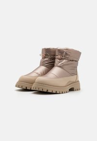 Bottes d'hiver rembourrées en taupe métallique avec un extérieur texturé, semelle en caoutchouc et col élastiqué. Dispose d'une semelle épaisse pour une meilleure adhérence.