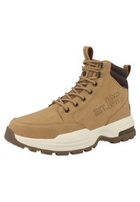 Bota alta de gamuza en color marrón claro con una suela media blanca. Presenta detalles en marrón, diseño con cordones y texto en relieve "EST. 1973." en el lateral.