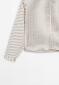 Chemise à manches longues beige et blanche à rayures verticales, coupe ample et ourlet légèrement raccourci.