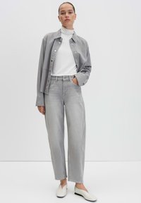Gray denim shirt over a white turtleneck, paired with light gray wide-leg pants and flat white shoes; smooth texture, button details.