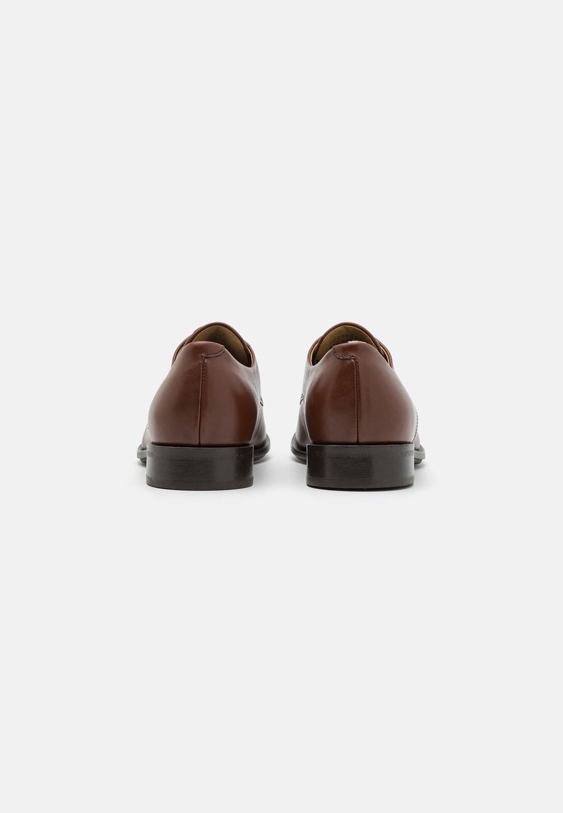 Brown leather shoes with a smooth finish, round toe, low heel, and minimal stitching detail, viewed from the back.