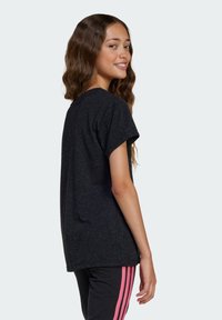 Čierne tričko s krátkym rukávom, vyrobené z textúrovaného materiálu, využívajúce voľný strih a zaoblený výstrih, nosené s čiernymi nohavicami a ružovými pruhmi.