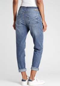 Vaaleansiniset farkut, joissa on rento malli, jalan päällä käänteet, takataskut ja sileä pinta. Korostettu hienovaraisella ompeleella.