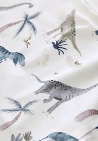 Tela blanca con ilustraciones impresas de varios dinosaurios, palmeras y plantas prehistóricas en colores suaves.