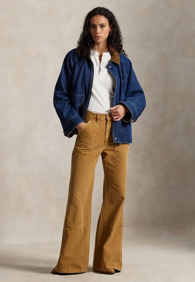 Temno modra denim jakna z rjavim ovratnikom, kombinirana s širokimi bež kordurovimi hlačami. Pod njo bela majica henley.