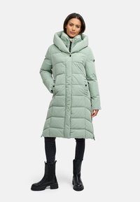 Gewatteerde lange jas in licht muntgroen, voorzien van een oversized capuchon, ritssluiting, drukknoopsluiting en zijzakken. Gecombineerd met zwarte enkellaarzen.