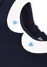 Ναυτικό μπλε ρούχο με λευκό γιακά που διαθέτει δύο κεντημένες ανοιχτό μπλε καρδιές. Ομαλή υφή, κλασικό σχήμα, σχεδιασμένο για άνεση.