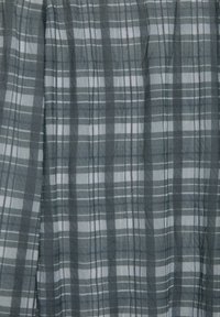 Szary i biały materiał w kratę z miękkimi pionowymi fałdami i subtelną fakturą, prezentujący jednolity wzór kraty.