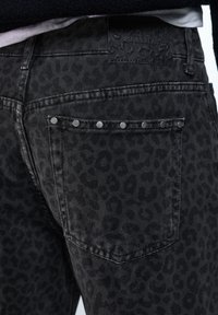 Schwarze Jeans aus Denim mit einem dezenten Leopardenmuster, silbernen Nietenakzenten auf der Gesäßtasche und einem markenprägten Lederpatch am Bund.