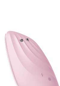 Brosse de nettoyage en silicone rose avec une forme incurvée et texturée. Comprend deux boutons brillants et de petites soies le long d'un bord.