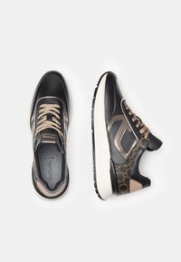 Sneaker in pelle nera con accenti beige, lati testurizzati e tessuto a motivo. Presentano suole bianche spesse e lacci decorativi.