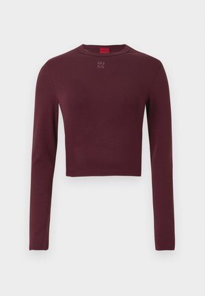 Burgundy long-sleeve crop top made of stretchy fabric, featuring a round neckline and embroidered "HUGO" text on the chest.