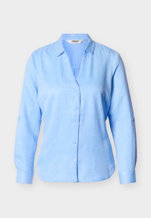 Camisa azul claro de manga larga con botones y cuello, hecha de tela ligera, mostrada sobre un fondo liso.