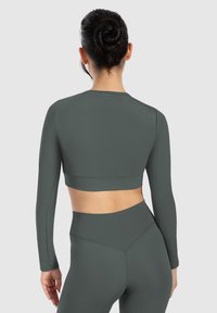 Langärmliges, verkürztes Oberteil in Dunkelgrün, aus glattem, dehnbarem Material gefertigt. Es hat ein tailliertes Design mit hohem Kragen und minimalen Nähten.