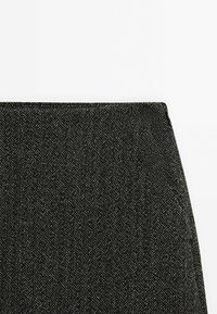 Black herringbone fabric featuring a textured weave with shades of gray. The top edge is finished with a clean, straight hem.