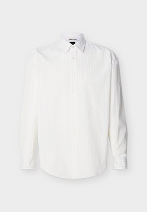 Chemise blanche à manches longues avec boutons, rayures verticales discrètes et col pointu, présentée à plat sur un fond clair.