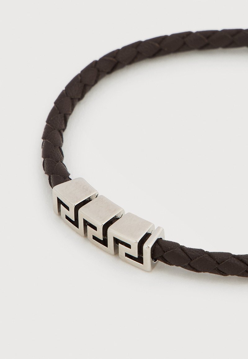 Geflochtenes Armband aus dunkelbraunem Leder mit silbernen Metallblöcken und geometrischen Ausschnitten. Glatte Textur mit kontrastierendem Design.