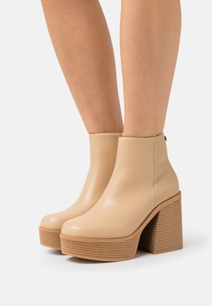 Beige enkellaarzen van glad leer, met een ronde neus en een ribbelige houten blokhak voor stabiliteit en stijl.