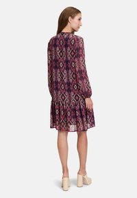 Short-sleeve dress with a tiered hem, featuring a purple and pink diamond pattern. Made of lightweight fabric with a relaxed fit.