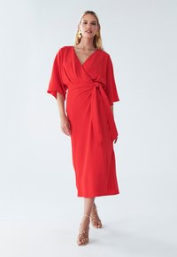 Rotes Wickelkleid mit kurzen Kimonoärmeln, passendem Bindegürtel in der Taille und mittellanger Schnittführung. Glattes Material in einer lebendigen, einfarbigen Ausführung.