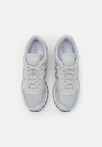 Gray mesh and synthetic upper sneakers with laces, padded collar, reflective accents, and a black rubber sole. Features a large logo on the side.