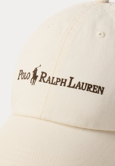 Καπέλο εκρού με καφέ κεντημένο λογότυπο Polo Ralph Lauren που απεικονίζει παίκτη πόλο πάνω σε άλογο, τοποθετημένο ακριβώς πάνω από το γείσο.