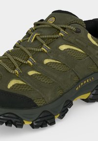 Πράσινο και κίτρινο ορειβατικό παπούτσι Merrell με χοντρή μαύρη και κίτρινη σόλα με τάπητα και σχεδιασμένα κίτρινο-πράσινα κορδόνια.