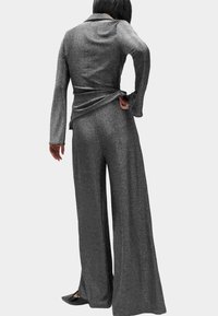 Grijs, metaalachtig gevarieerd outfit met een lang mouwtop met een wikkeldesign en een brede broek. De stof heeft een glanzende afwerking.