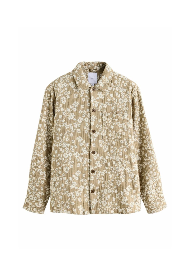 Cămașă cu imprimeu floral din material bej cu modele albe, cu închidere prin butoni, și un design clasic al gulerului. Prezintă mâneci lungi și un buzunar pe piept.