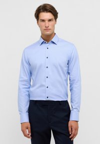 Lichtblauw button-up shirt met een klassieke kraag, lange mouwen en donkere knopen. Gladde textuur, getailleerd ontwerp, gecombineerd met donkere broeken.