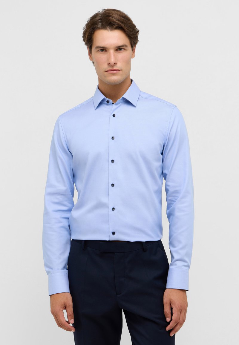 Lichtblauw button-up shirt met een klassieke kraag, lange mouwen en donkere knopen. Gladde textuur, getailleerd ontwerp, gecombineerd met donkere broeken.