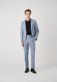 Lichtblauw pak gemaakt van textuurstof, met een slim fit, blazer met één knoop en bijpassende broek, gecombineerd met een zwart T-shirt en zwarte schoenen.