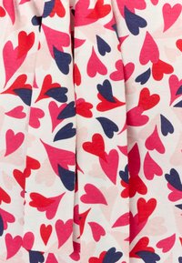 Multikleurige stof met roze, rode en marineblauwe harten op een crème achtergrond, met een gladde textuur en een lichte glans.