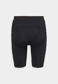 Shorts de sport noirs taille haute, ajustés et avec des coutures de contour visibles à l’arrière, présentés sur un fond uni clair.