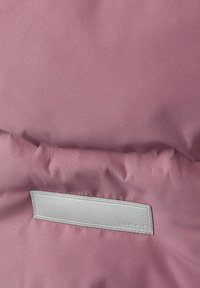 Roosa välimine kangas, millel on sile tekstuur. Sellel on hall nahkplekk, millel on silt "nime see". Pehme, polsterdatud disain.