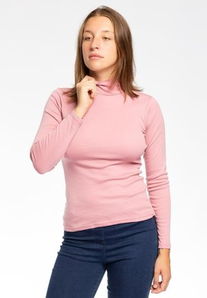 Maglietta rosa a maniche lunghe con colletto alto, realizzata in tessuto morbido e liscio, con un design aderente, abbinata a jeans di denim blu scuro.