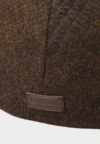 Brown wool hat featuring a textured surface with flecks of golden fibers, and a leather tag embossed with "Barbour England."