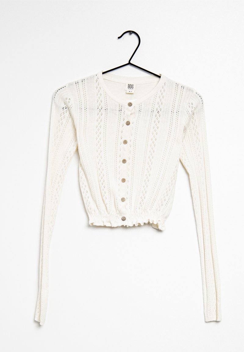 White knitted long-sleeve cropped cardigan with vertical eyelet patterns, button-down front, and ruffled hem on a black hanger.