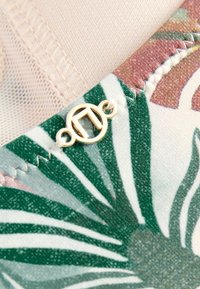 Stoff mit floralem Muster und grünen Blattdesigns, ausgestattet mit einem goldenen metallischen Verschluss und feinen Stickdetails. Weiche Textur und gedeckte Farben.
