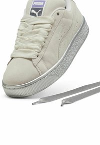 Puma tossud pehmeast, beežist nahast ülemisest osast, millel on hõbedane kummist sisetald ja tasasel koorusel kreemjad paelad. Kaasas on kaks täiendavat hõbedast paela.