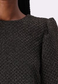 Zwarte textuurstof top met metalen draden, ronde halslijn en pofmouwen. Kenmerkt een subtiel patroon voor extra diepte.