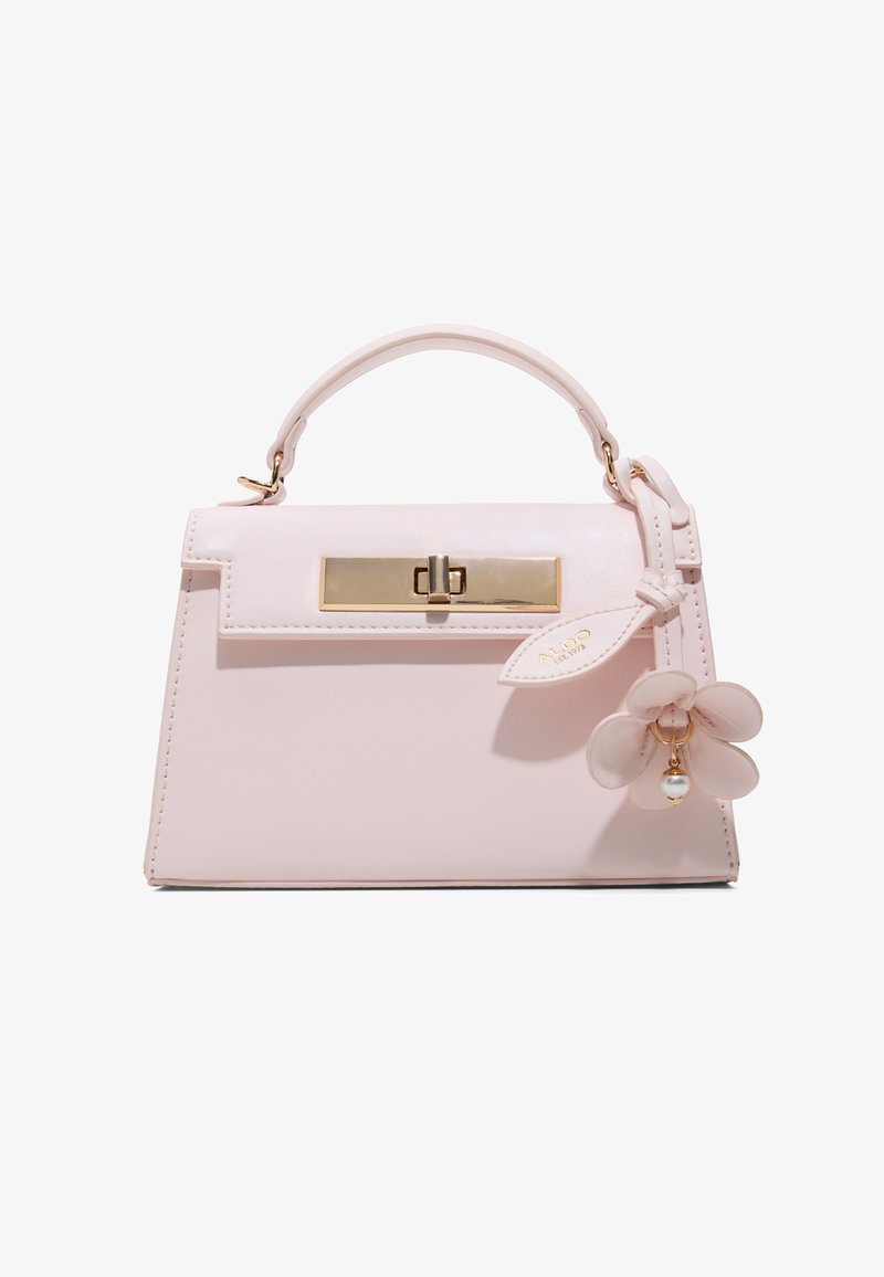 Petit sac à main rose clair avec poignée supérieure, fermoir doré et un charm décoratif en forme de fleur avec détail en perle sur le côté droit.