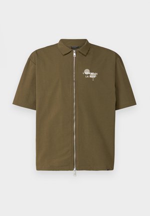 Srajca kratkih rokavov olivno zelene barve s sprednjim zadrgo in belim tiskanim napisom "L'HOMME DE LA NUIT" na levi strani. Gladka tekstura blaga.