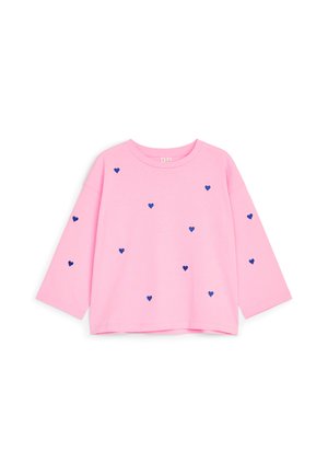 Chemise rose à manches longues avec un col rond, décorée de petites formes de cœur bleu marine dispersées sur le devant et les manches.