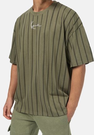 Olivgrünes Baumwoll-T-Shirt mit schwarzen vertikalen Streifen. Es hat eine lockere Passform, kurze Ärmel und ein kleines weißes Logo auf der Brust.