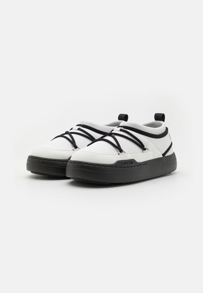 Adidași albi cu șireturi elastice negre, bot rotund, guler căptușit, talpă de cauciuc neagră și design minimalist. Accentuati cu detalii de brand.
